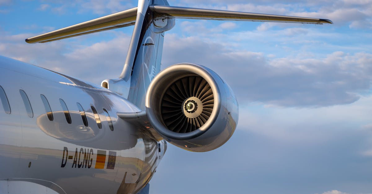 detailed view of a jet engine and tail against a blue sky with clouds